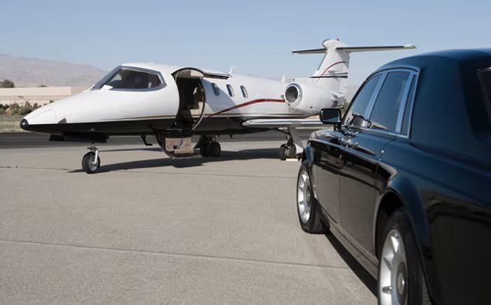 Chauffeured car beside a private jet