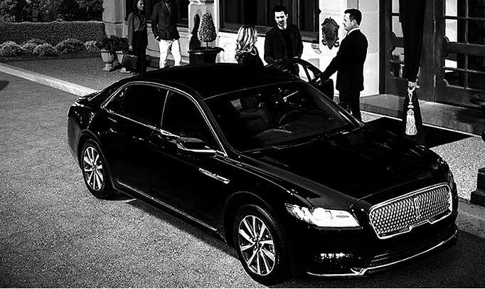 Chauffeur with a black sedan outside a venue